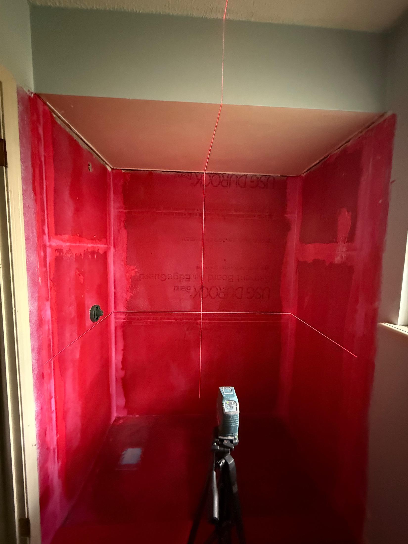 Shower stripped to waterproofed cement board, laser level line on the wall